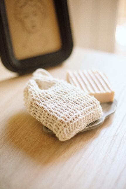 Minimalist photo of a handcrafted soap bar paired with a crochet soap bag on a rustic wooden table.